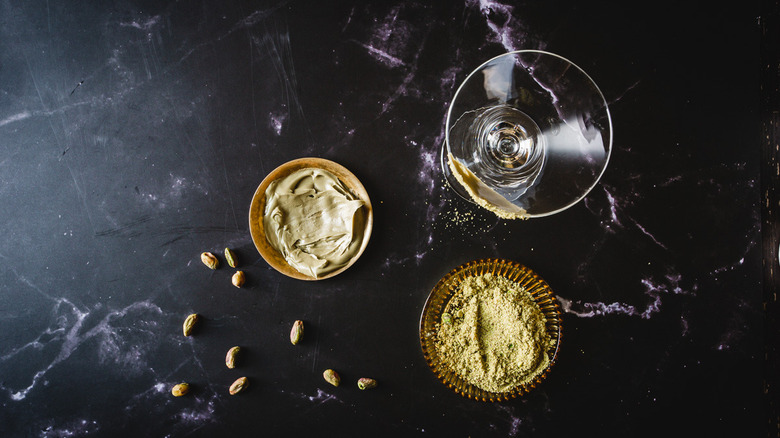 Rimmed martini glass with pistachio spread and ground pistachios.