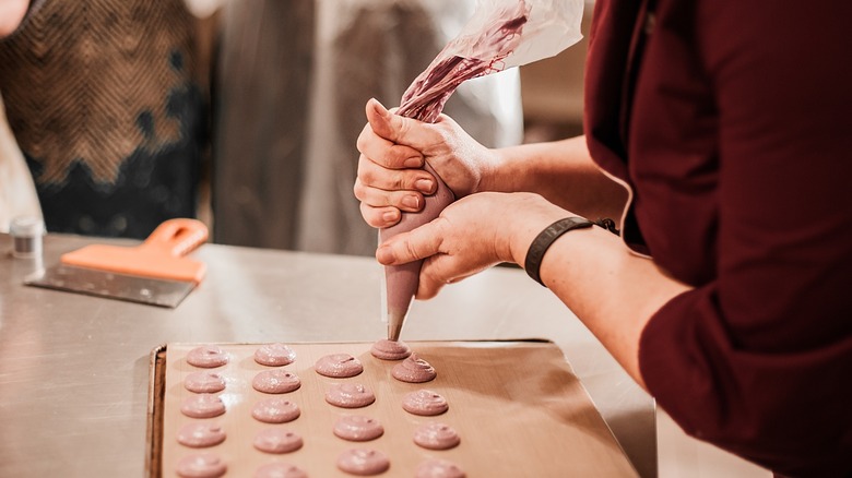 Person piping macaron batter