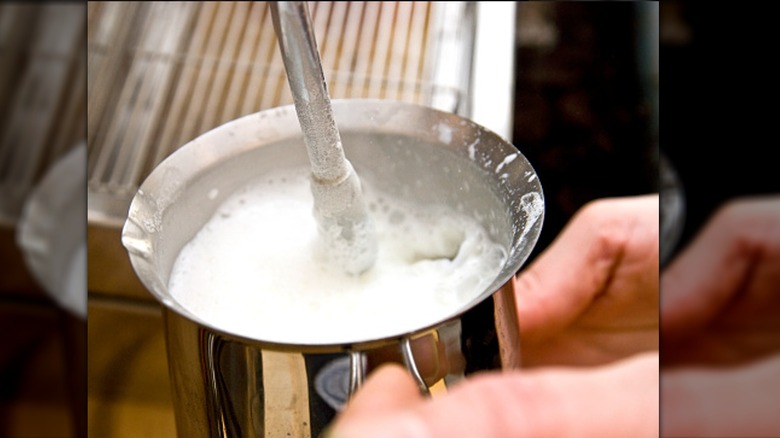 Barista steaming a pitcher of milk
