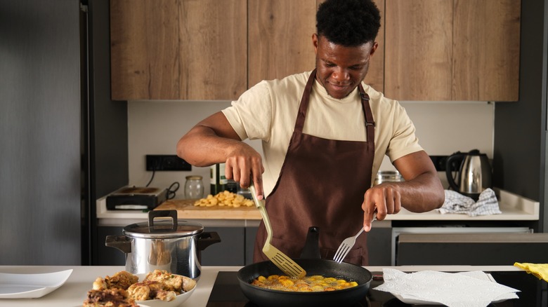 man frying plantains in kitchen