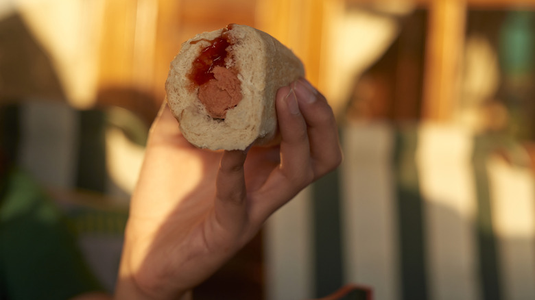 Foodie hoisting a red snapper into the air on a plush New England split-top bun