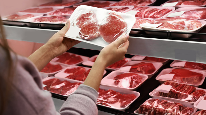 Person holding packaged pork supermarket 