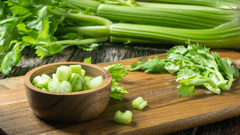 Chopped celery stalks in a bowl on a cutting board