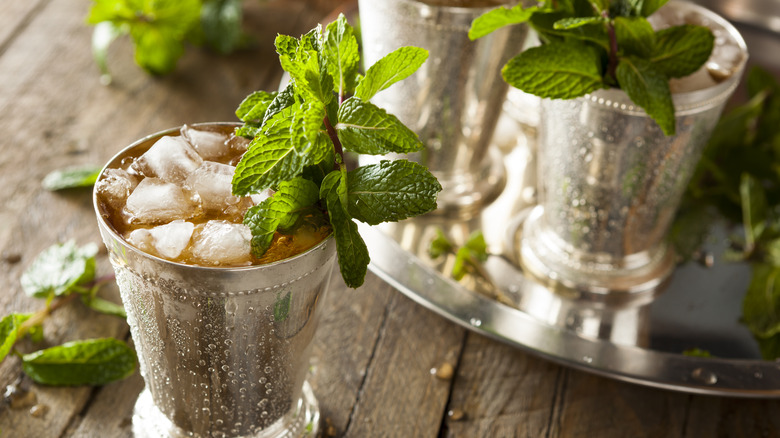 mint julep in a metal cup on a wood table