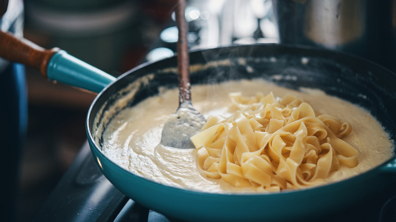 Stirring pasta into alfredo sauce