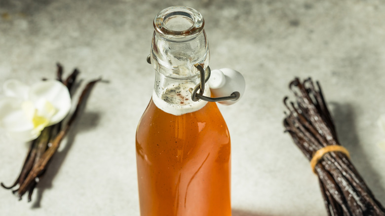 A jar of vanilla simple syrup surrounded by vanilla beans
