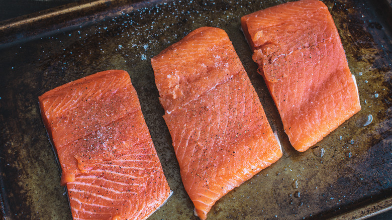 The salmon filets laying on an oily tray.