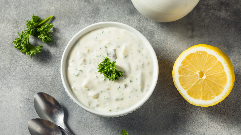 tartar sauce in a bowl with parsley and lemon surrounding