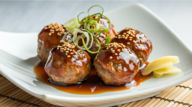 bowl of glazed meatballs garnished with green onions