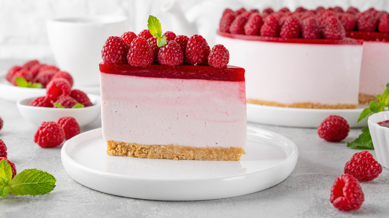no bake raspberry cheesecake slide separated from whole cake with fresh raspberries around