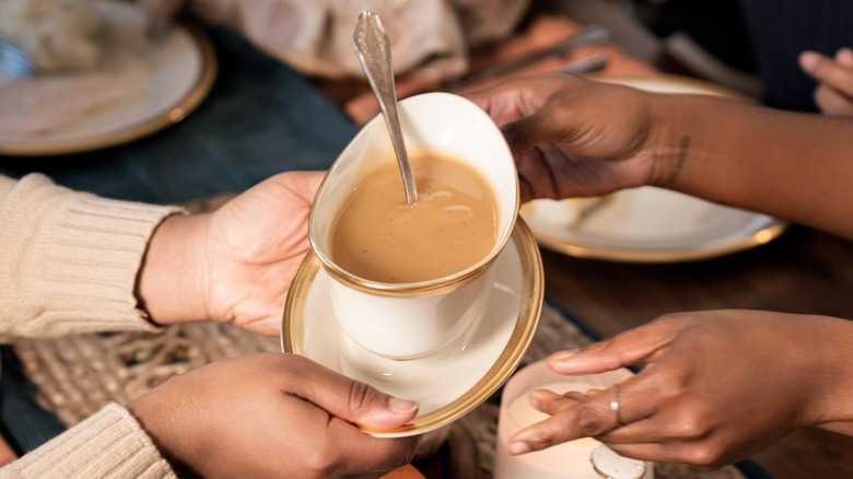 Hands passing serving dish of gravy