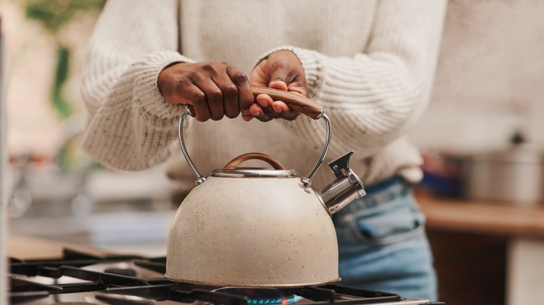 woman lifting a kettle from stovetop