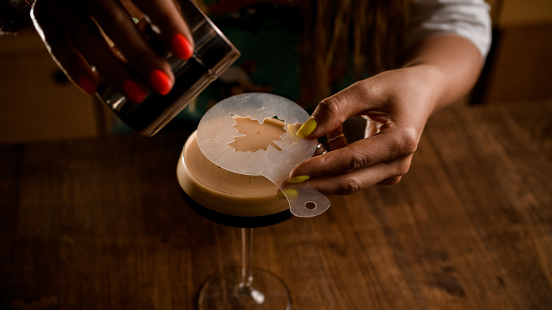 bartender using stencil on cocktail