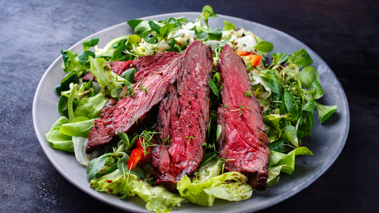 sliced grilled steak on top of salad