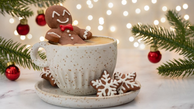 Gingerbread cookie sitting in hot chocolate cup with holiday decorations