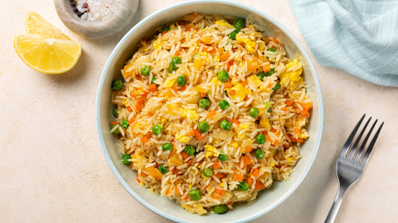 Bowl of fried rice beside lemon and fork