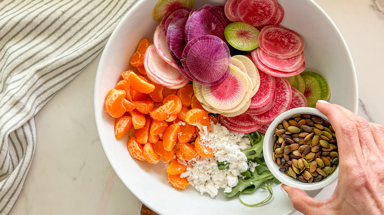 hand adding cheese to salad