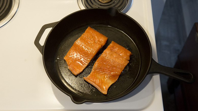 salmon cooking in iron pan