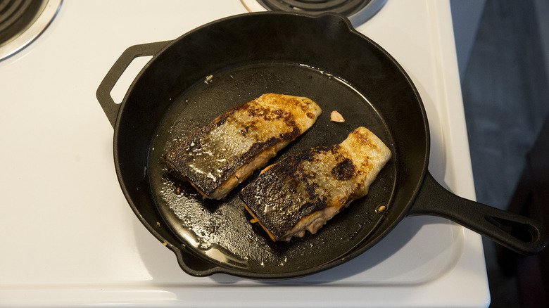 salmon frying in iron pan