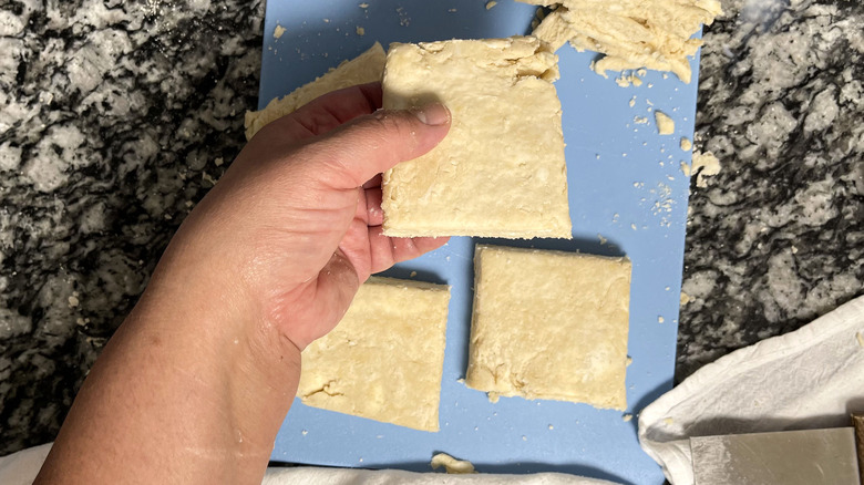 hand holding square biscuit dough