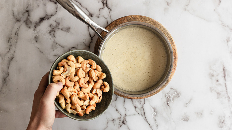 Adding cashews to pan with toffee