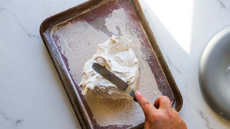 Hand spreading marshmallow mixture