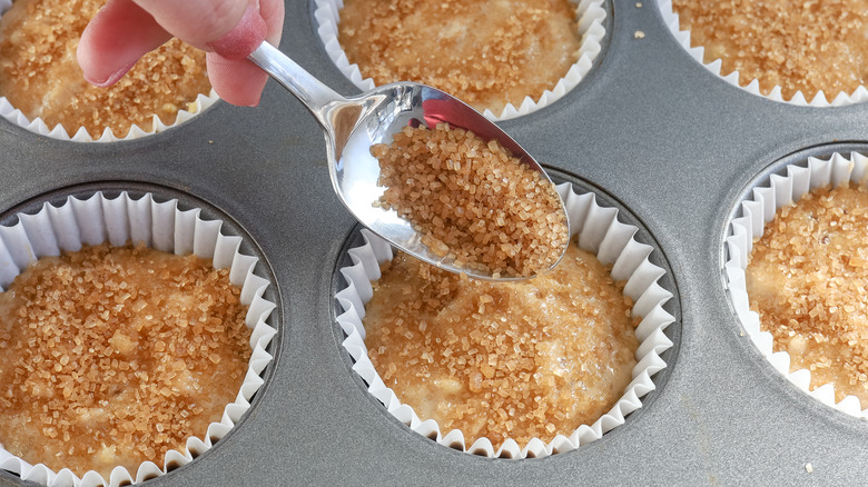 spooning sugar onto muffin batter