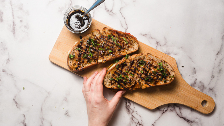 Hand holding sandwich drizzled with balsamic reduction