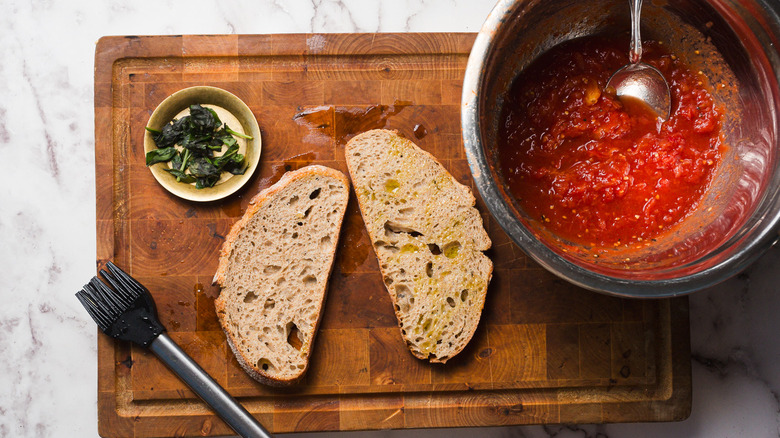 Oiled bread pieces on cutting board next to bowl of tomato sauce