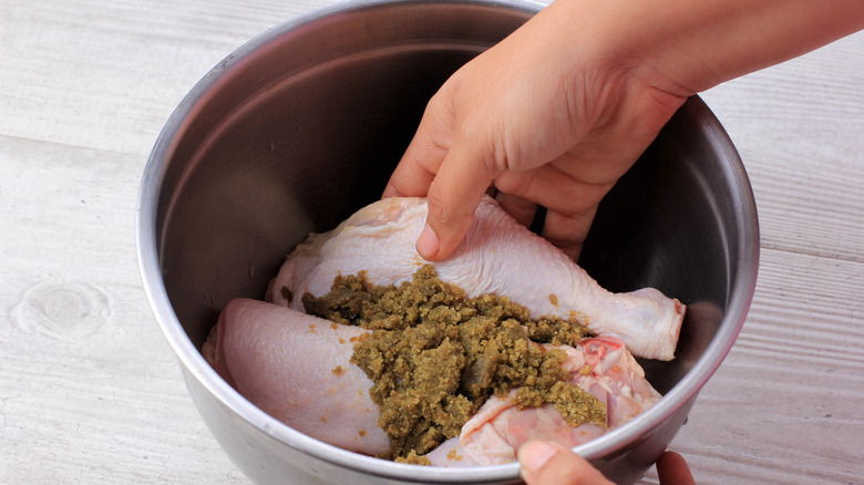 hand applying dry rub to drumsticks