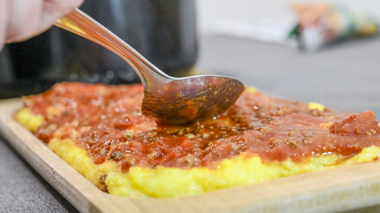 large spoon covering polenta in sauce