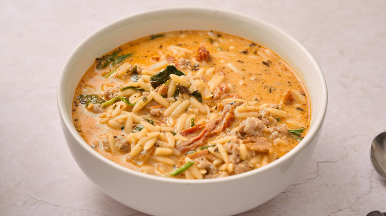 Italian sausage and orzo soup in a white bowl