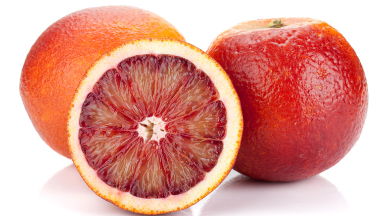 Whole and cut blood oranges on a white background
