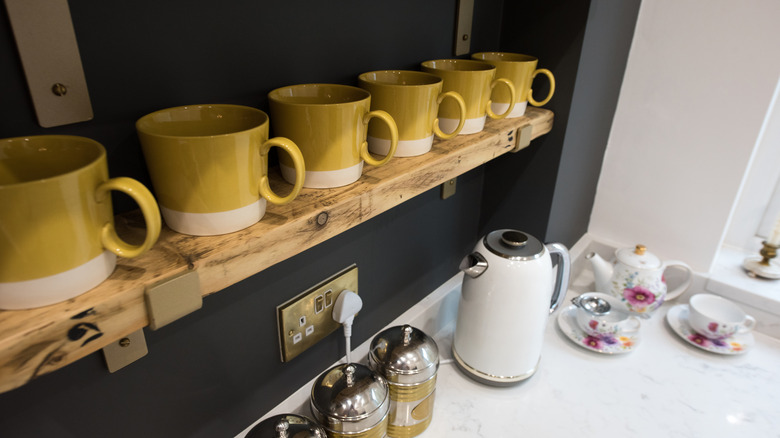 An open kitchen shelf above counter decorated with mugs
