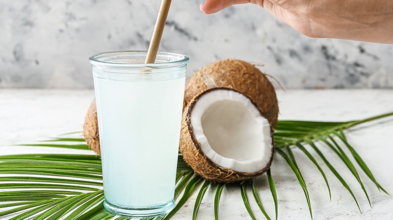 Cup of coconut water in front of cracked coconuts