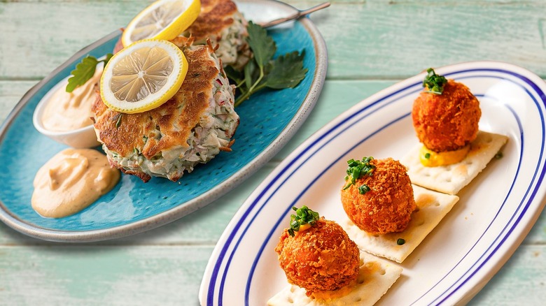 Crabcakes and coddies on separate plates side by side