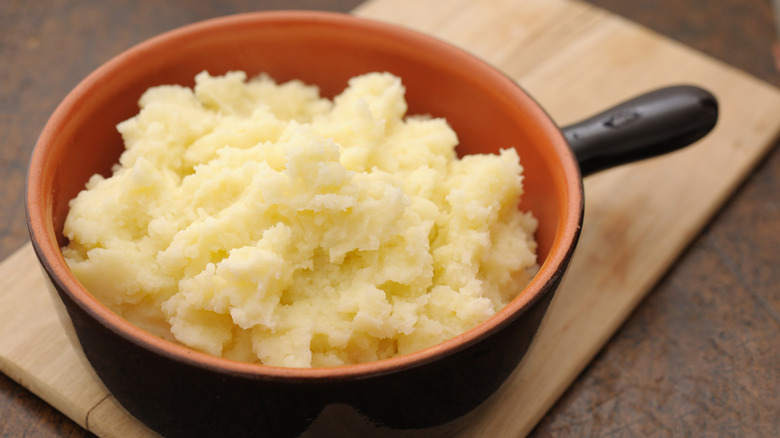 Pot of mashed potatoes on cutting board 