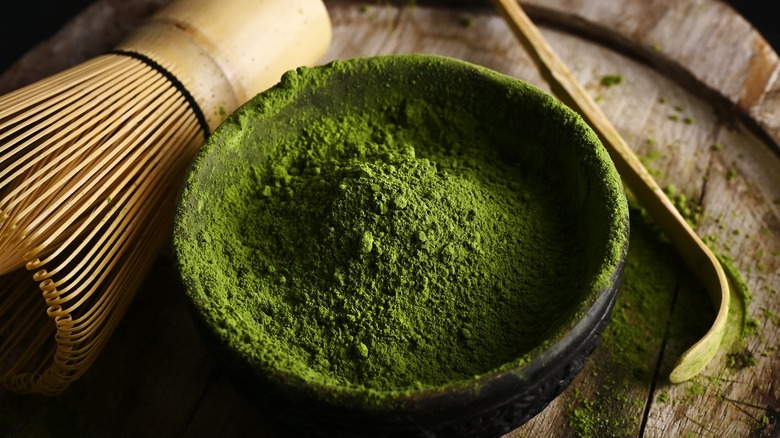 matcha powder next to wooden whisk