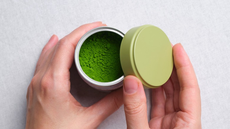 hands holding tin of matcha