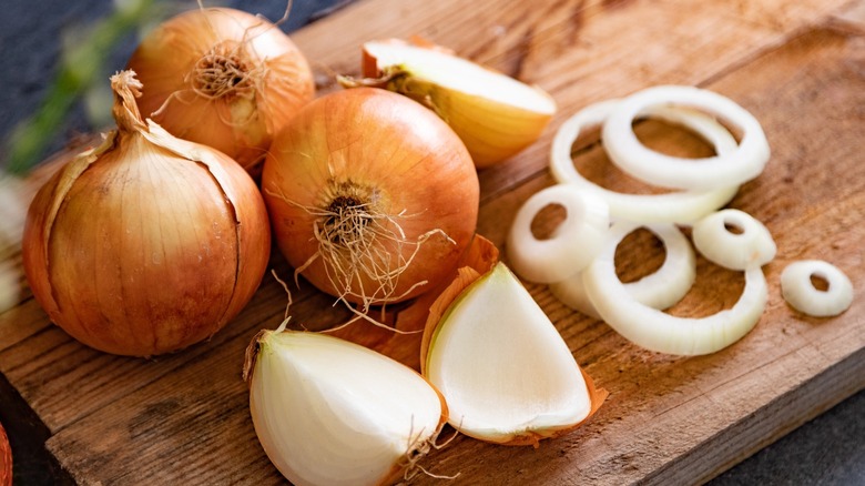 Whole and sliced onions on a cutting board