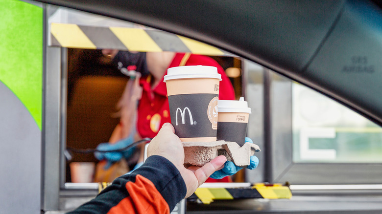 McDonald's employee handing patron a drive-thru food order