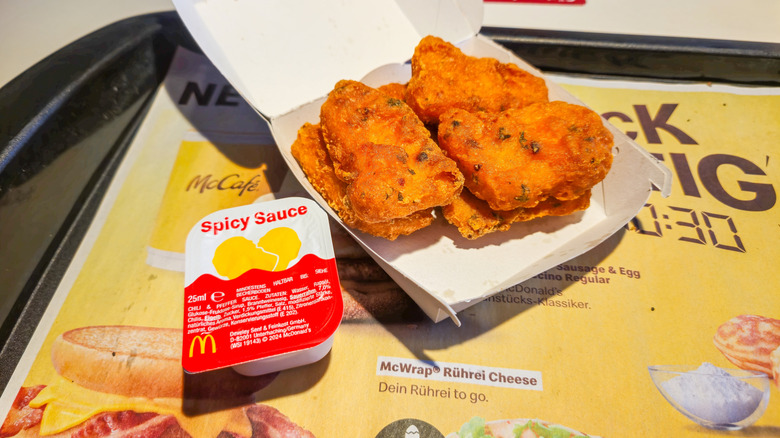 Box of spicy McNuggets beside a spicy sauce packet
