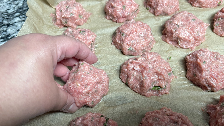 hand placing meatball on sheet