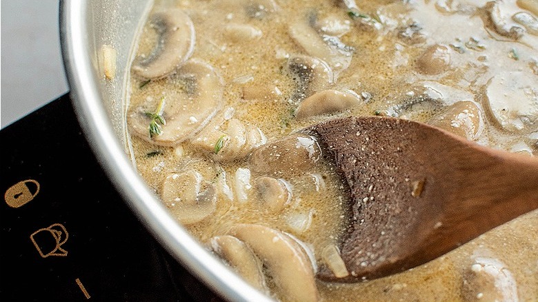 stirring cream sauce in skillet