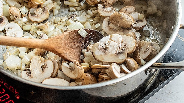 stirring mushrooms in skillet
