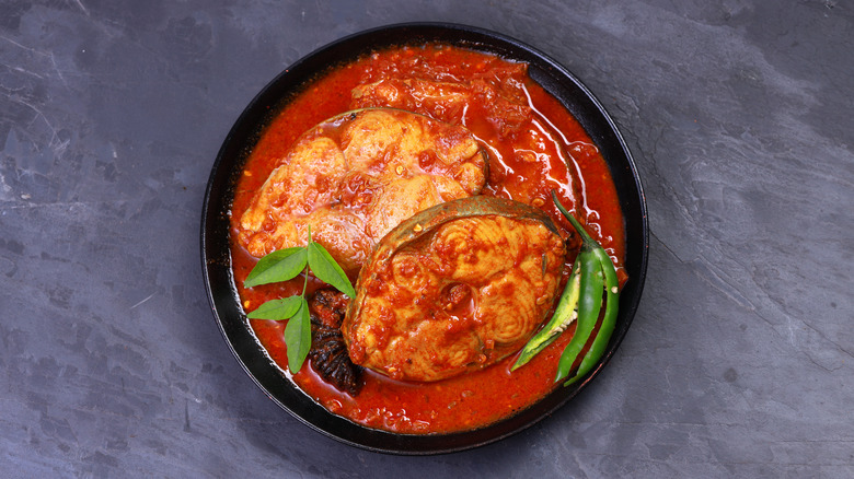 Kerala fish curry with fresh chilies in a black bowl