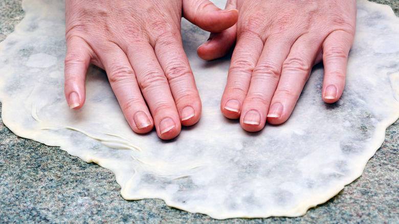 hands spreading dough