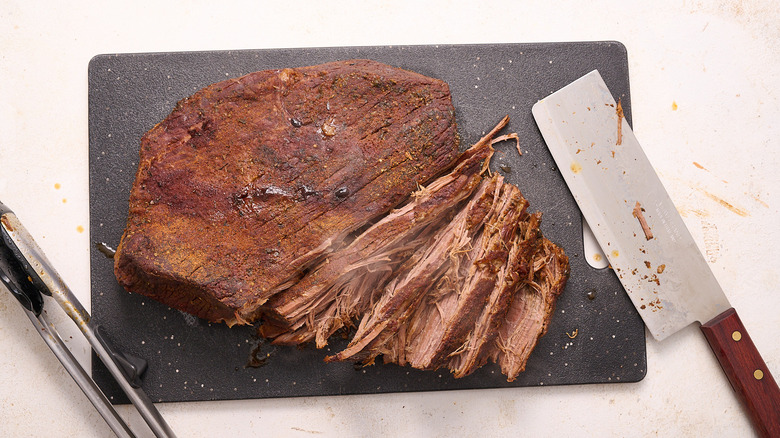 Slicing roasted brisket on cutting board