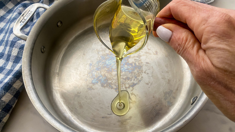 hand adding oil to pan