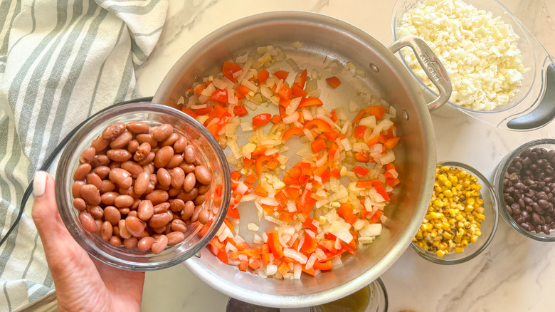 hand adding beans to pan